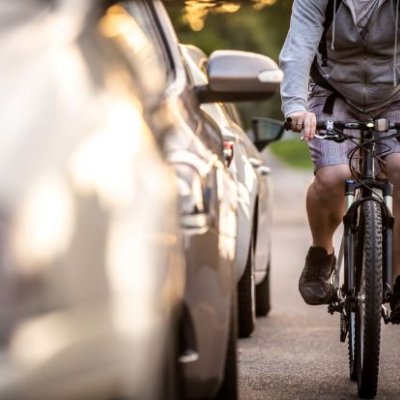 a cyclist riding close to a line of cars